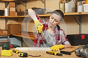 Beautiful caucasian young brown-hair woman working in carpentry workshop at table place.