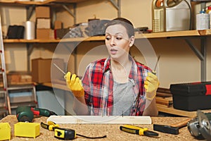 Beautiful caucasian young brown-hair woman working in carpentry workshop at table place.