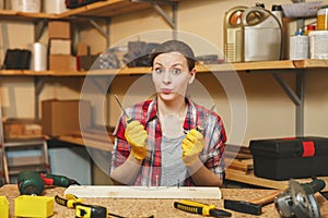 Beautiful caucasian young brown-hair woman working in carpentry workshop at table place.