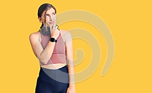 Beautiful caucasian young woman wearing gym clothes and using headphones thinking worried about a question, concerned and nervous