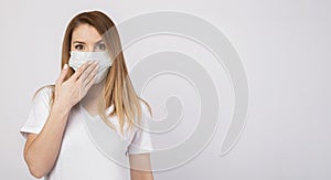 Beautiful caucasian young woman in white t-shirt with disposable face mask. Protection versus viruses and infection. Studio