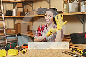 Beautiful caucasian young woman working in carpentry workshop at table place