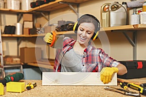 Beautiful caucasian young woman working in carpentry workshop at table place