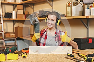 Beautiful caucasian young woman working in carpentry workshop at table place