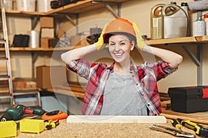 Beautiful caucasian young woman working in carpentry workshop at table place