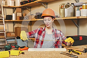 Beautiful caucasian young woman working in carpentry workshop at table place