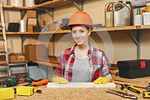 Beautiful caucasian young woman working in carpentry workshop at table place