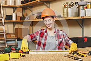 Beautiful caucasian young woman working in carpentry workshop at table place