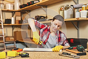 Beautiful caucasian young woman working in carpentry workshop at table place