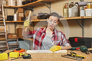 Beautiful caucasian young woman working in carpentry workshop at table place