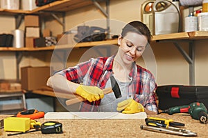 Beautiful caucasian young woman working in carpentry workshop at table place