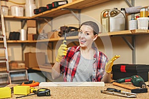 Beautiful caucasian young woman working in carpentry workshop at table place