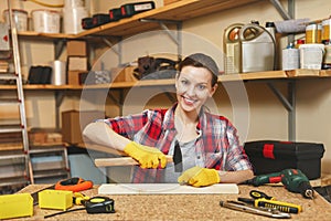 Beautiful caucasian young woman working in carpentry workshop at table place