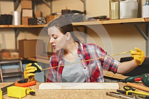 Beautiful caucasian young woman working in carpentry workshop at table place