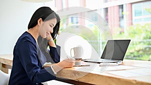 Beautiful charming asian businesswoman working at her modern bright office desk