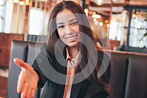 Beautiful charming brunette happy asian girl young woman giving handshake, hand of help, greeting at cafe