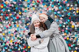 Beautiful charming smiling young teenage girls two sisters having fun posing against a colorful bright wall