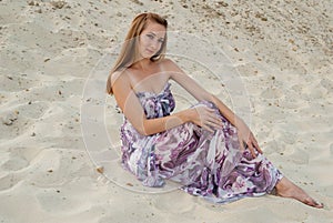 Beautiful charming woman with open shoulders on sand