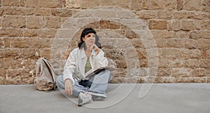 Beautiful charming woman sitting at the floor near to wall