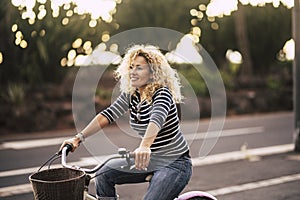 Beautiful and cheerful adult young woman enjoy bike ride in sunny urban outdoor leisure activity in the city - happy people