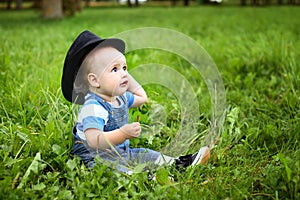 Beautiful cheerful boy with black hat in summer park