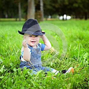 Beautiful cheerful boy with black hat in summer park