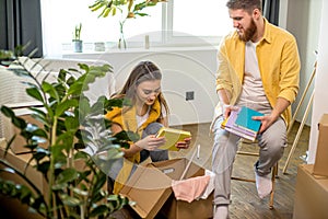 Beautiful cheerful couple unpack cardboard boxes with books