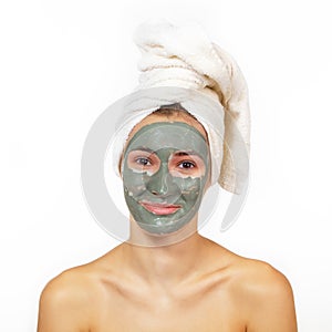 Beautiful cheerful girl applying facial clay mask. Young woman and beauty treatments over white background. Pampering, youth, anti