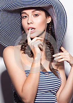 Beautiful cheerful girl in a summer beach striped hat. The beauty of the face.