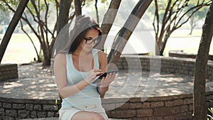 Beautiful Cheerful Girl With a Tablet PC Sitting In a Park on a Bench on a Sunny Day, On-line Shopping Concept