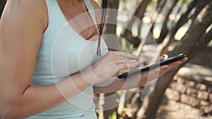 Beautiful Cheerful Girl With a Tablet PC Sitting In a Park on a Bench on a Sunny Day, On-line Shopping Concept