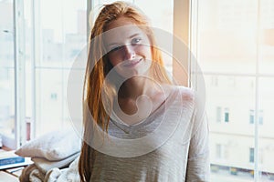 Beautiful cheerful happy young smiling redhead girl, morning sunrise light, waking up early