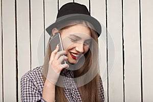 Beautiful, cheerful, joyful,happy girl in shirt and hat talking on the phone
