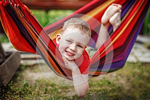 Beautiful cheerful little boy resting in a hammock