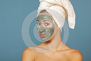 Beautiful cheerful teen girl applying facial clay mask. Beauty treatments