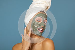 Beautiful cheerful teen girl applying facial clay mask. Beauty treatments