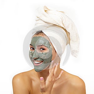 Beautiful cheerful teen girl applying facial clay mask. Beauty treatments, isolated over white