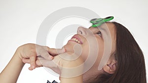 Beautiful cheerful teen girl spinning a green fidget spinner on her forehead on white background