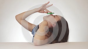 Beautiful cheerful teen girl spinning green fidget spinner on her nose on white background