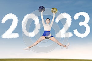 Beautiful cheerleader girl jumping with 2023 number