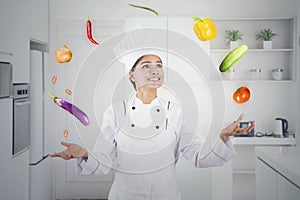 Beautiful chef juggling food ingredients in kitchen