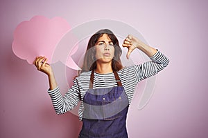 Beautiful chef woman wearing apron holding cloud speech bubble over isolated pink background with angry face, negative sign