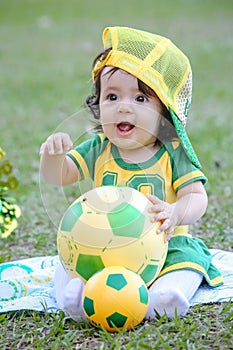 Beautiful child of the Brazilian soccer team in a park, dressed up in green and yellow.