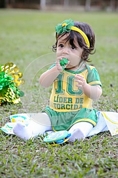Beautiful child of the Brazilian soccer team in a park, dressed up in green and yellow.