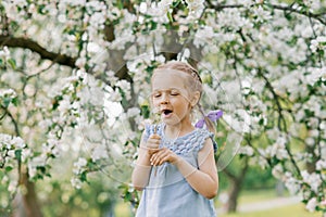 Beautiful child with dandelion flower. Happy kid having fun outdoors in spring park