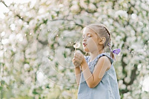 Beautiful child with dandelion flower. Happy kid having fun outdoors in spring park