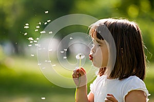 Beautiful child with dandelion flower in spring park. Happy kid having fun outdoors.