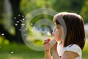 Beautiful child with dandelion flower in spring park. Happy kid having fun outdoors.