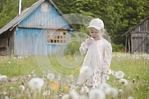Beautiful child with dandelion flowers in park in summer. Happy kid having fun outdoors.