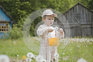 Beautiful child with dandelion flowers in park in summer. Happy kid having fun outdoors.